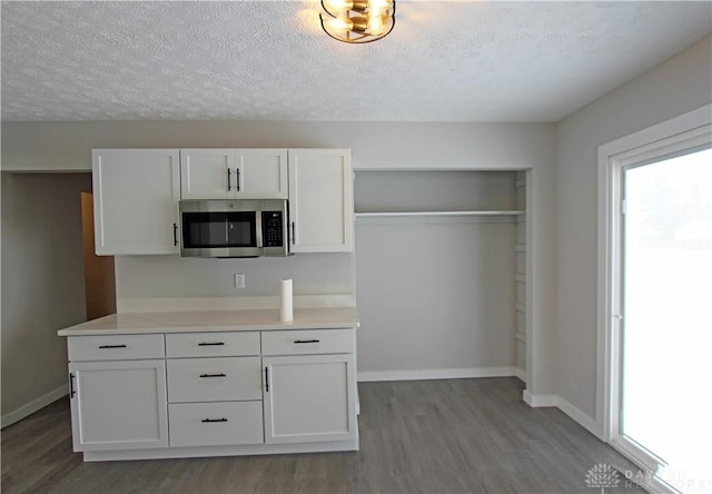 kitchen featuring white cabinets, a textured ceiling, and light wood-type flooring