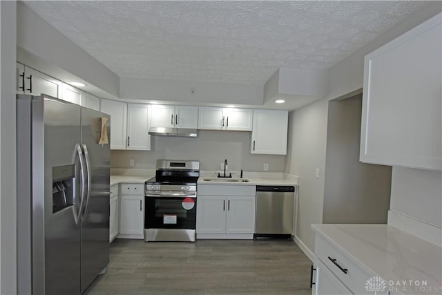 kitchen featuring dark hardwood / wood-style flooring, a textured ceiling, stainless steel appliances, sink, and white cabinetry