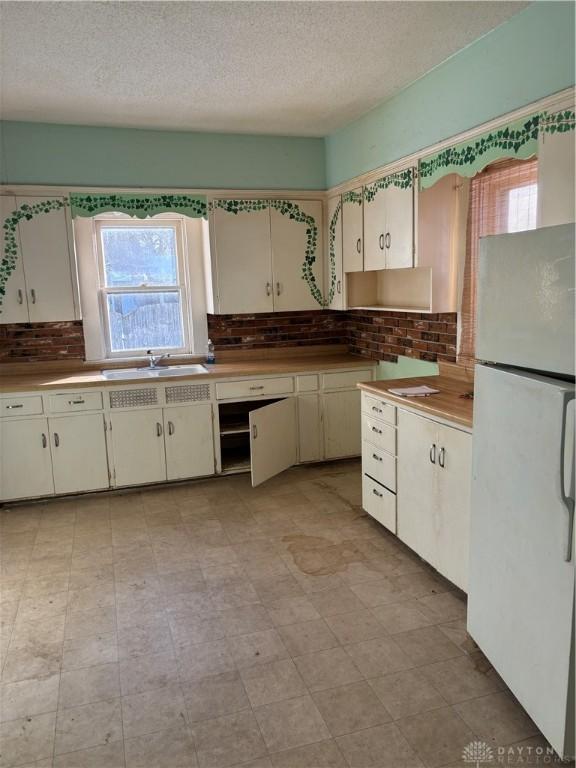 kitchen featuring white refrigerator, a textured ceiling, and a wealth of natural light