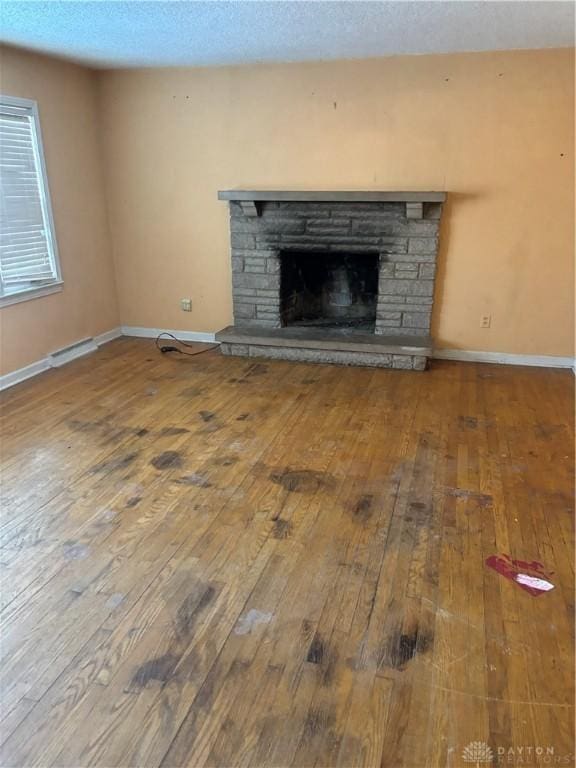 unfurnished living room featuring a stone fireplace and wood-type flooring