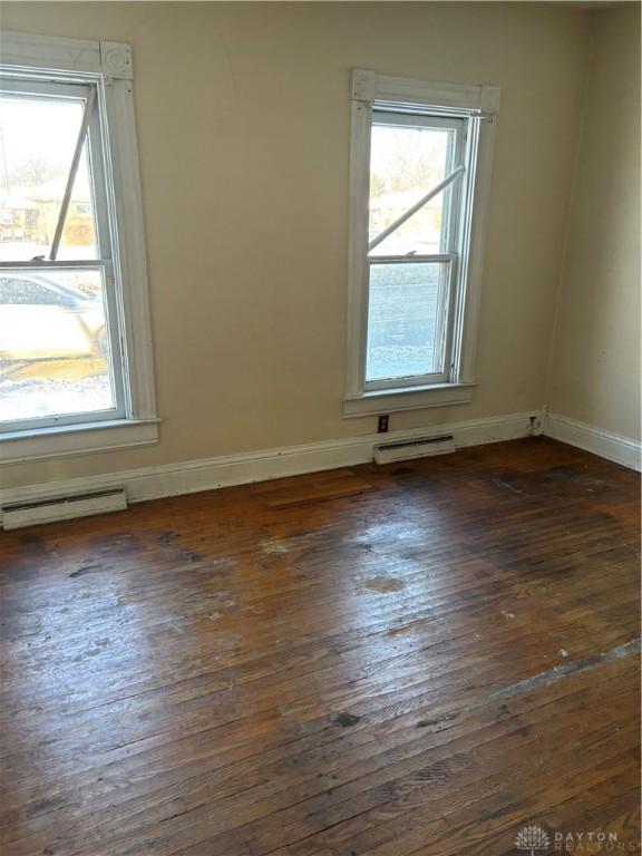 empty room with dark wood-type flooring and a wealth of natural light