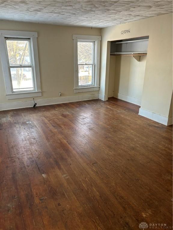 unfurnished bedroom featuring multiple windows, a closet, and dark wood-type flooring