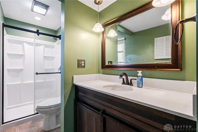 bathroom with tile patterned flooring, a shower with door, vanity, and toilet