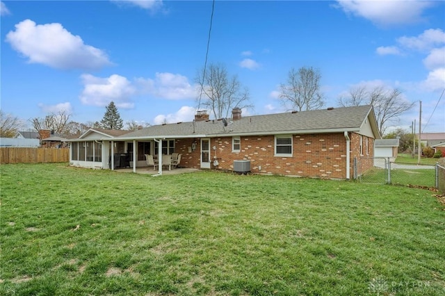 rear view of house featuring a lawn, central AC, a sunroom, and a patio area