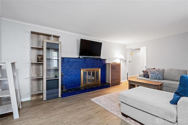 living room with wood-type flooring, ornamental molding, and a brick fireplace