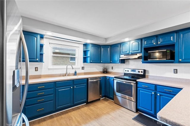 kitchen with blue cabinetry, stainless steel appliances, light hardwood / wood-style floors, and sink