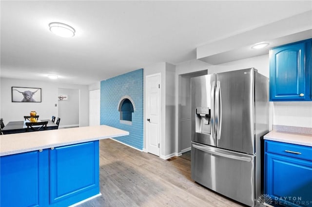 kitchen with blue cabinetry, stainless steel fridge, and light hardwood / wood-style floors