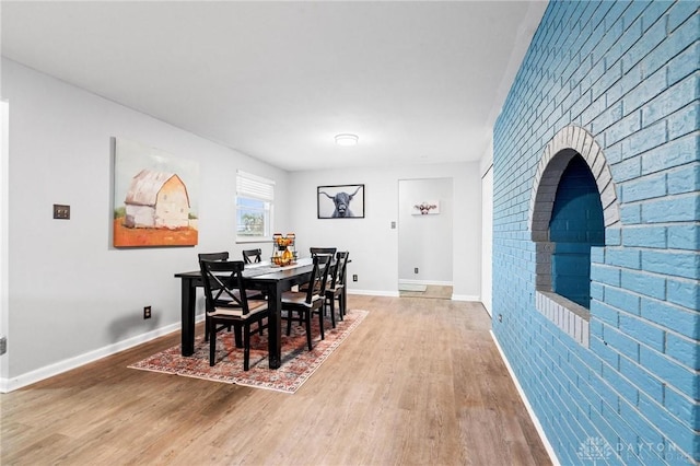 dining room with wood-type flooring and brick wall