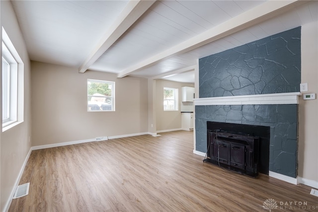 unfurnished living room with a fireplace, hardwood / wood-style floors, and beam ceiling