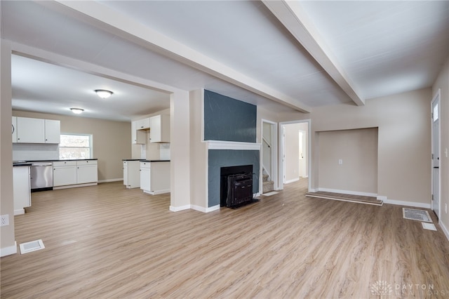 unfurnished living room featuring beam ceiling and light hardwood / wood-style flooring