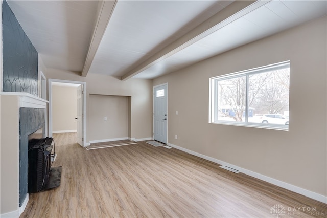 unfurnished living room with light hardwood / wood-style flooring, beamed ceiling, and plenty of natural light