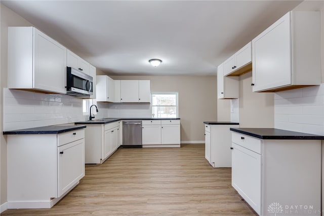 kitchen with white cabinetry, sink, stainless steel appliances, light hardwood / wood-style flooring, and decorative backsplash