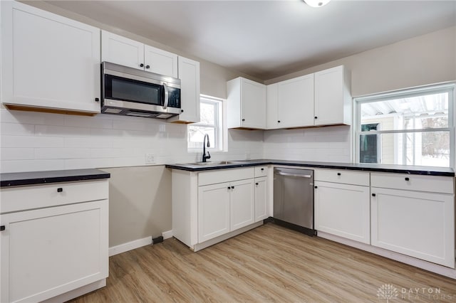 kitchen with sink, white cabinets, stainless steel appliances, and light wood-type flooring