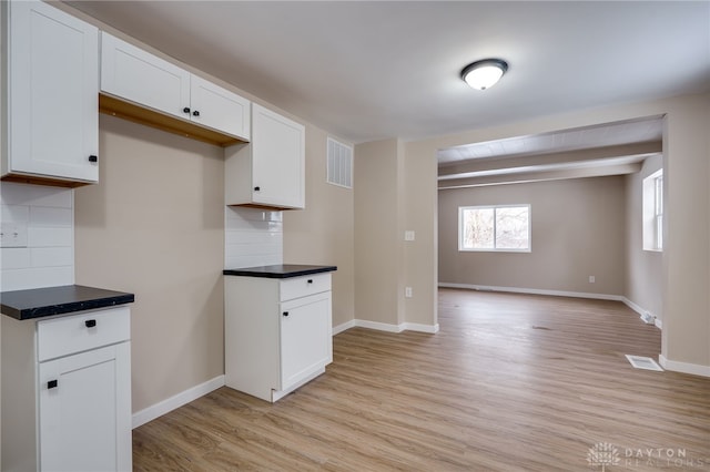 kitchen featuring white cabinets, decorative backsplash, and light wood-type flooring