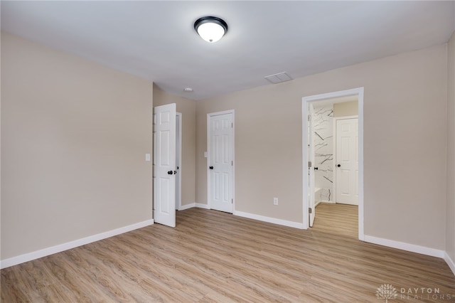 unfurnished bedroom featuring light wood-type flooring and ensuite bathroom