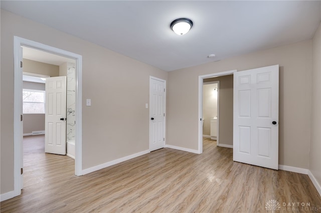 unfurnished bedroom with light hardwood / wood-style flooring and ensuite bath