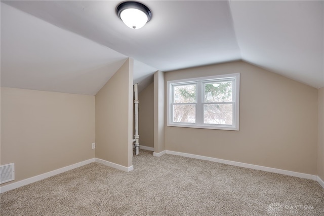 bonus room with light colored carpet and lofted ceiling