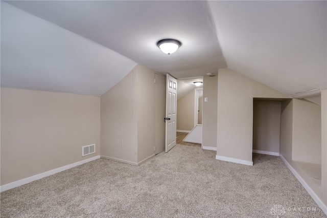 additional living space featuring light colored carpet and lofted ceiling