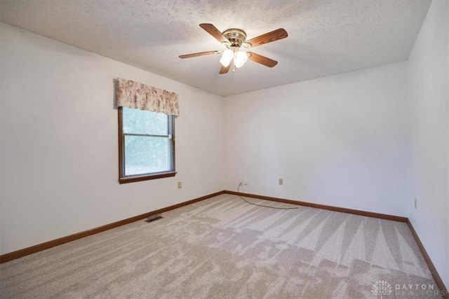 carpeted spare room featuring a textured ceiling and ceiling fan