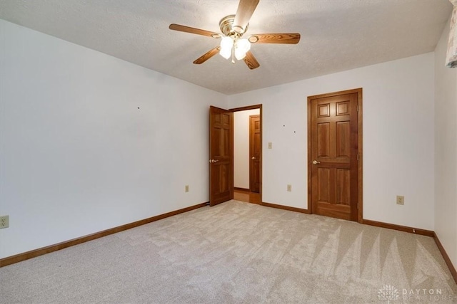 unfurnished bedroom featuring ceiling fan, light carpet, and a textured ceiling