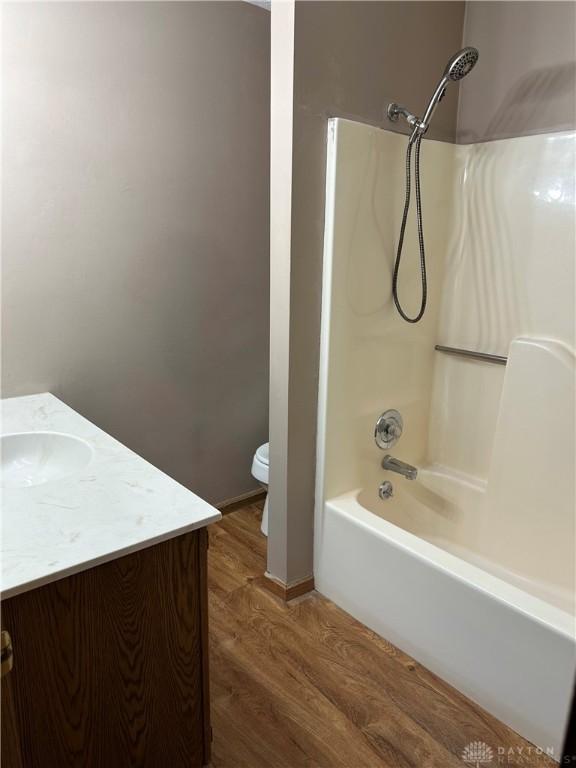 full bathroom with toilet, wood-type flooring, shower / washtub combination, and vanity