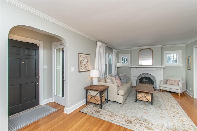 living room featuring a fireplace, wood-type flooring, and ornamental molding