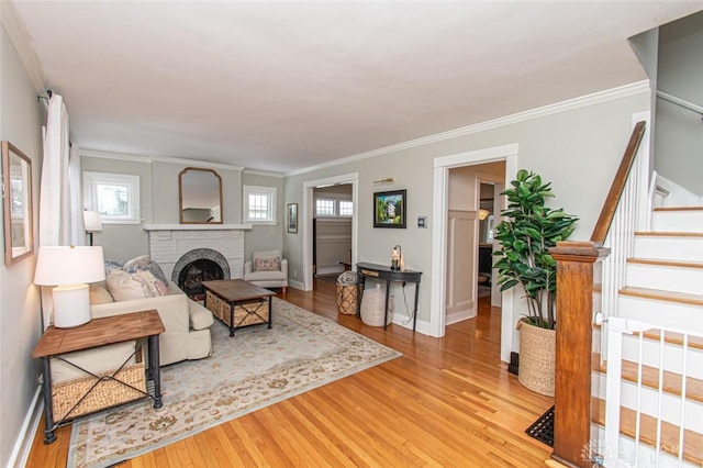 living room featuring a fireplace, ornamental molding, plenty of natural light, and light wood-type flooring