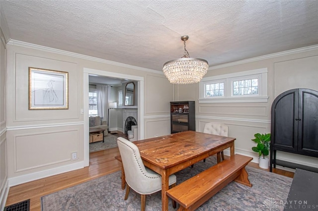 dining room featuring a healthy amount of sunlight, hardwood / wood-style floors, a textured ceiling, and a chandelier