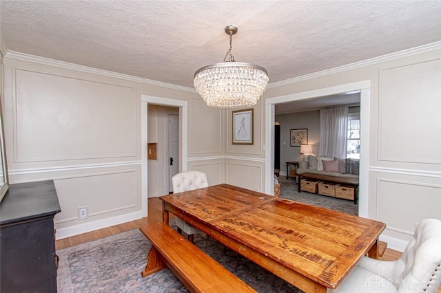 dining room with an inviting chandelier, ornamental molding, hardwood / wood-style floors, and a textured ceiling