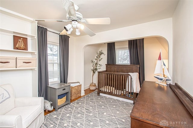 bedroom featuring a nursery area and ceiling fan