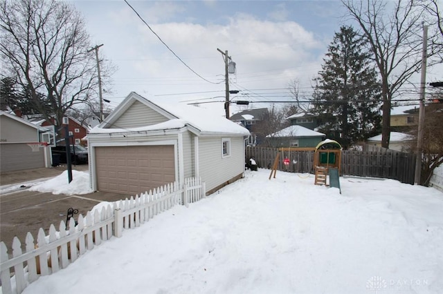 yard covered in snow with a garage and a playground