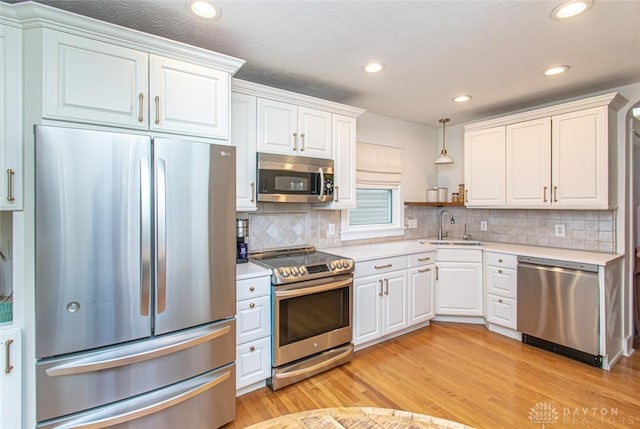 kitchen featuring white cabinetry, sink, light hardwood / wood-style flooring, and appliances with stainless steel finishes