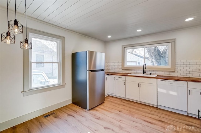 kitchen featuring white cabinetry, stainless steel refrigerator, dishwasher, and hanging light fixtures