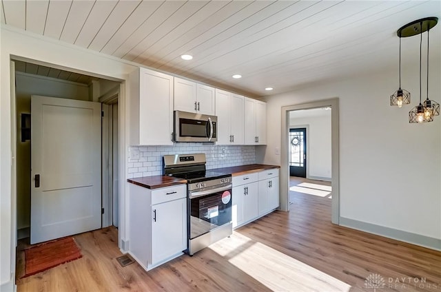 kitchen with appliances with stainless steel finishes, light hardwood / wood-style floors, wood counters, pendant lighting, and white cabinetry