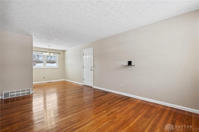 spare room featuring baseboards, visible vents, and wood finished floors