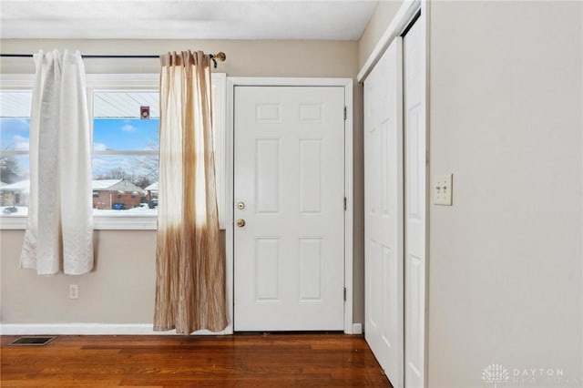 foyer entrance featuring baseboards, visible vents, and wood finished floors