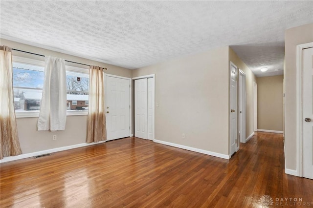 unfurnished room with dark wood-type flooring and a textured ceiling