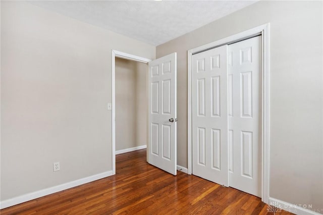 unfurnished bedroom featuring a closet, baseboards, and wood finished floors