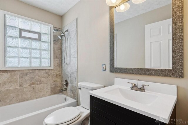 full bathroom featuring toilet, tiled shower / bath combo, and vanity