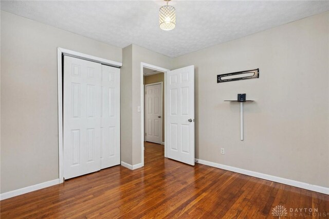 unfurnished bedroom with a closet, a textured ceiling, and dark hardwood / wood-style floors