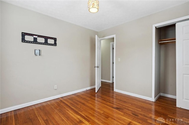 unfurnished bedroom featuring a closet, wood finished floors, and baseboards