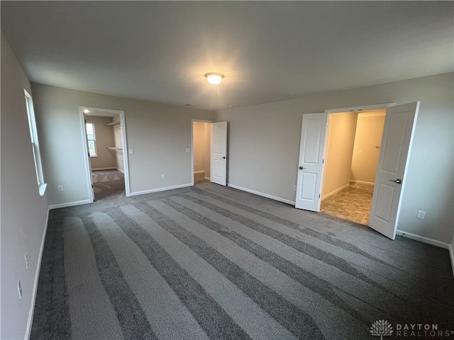 unfurnished bedroom featuring connected bathroom and dark carpet