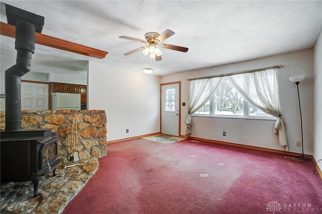 carpeted living room featuring ceiling fan and a wood stove