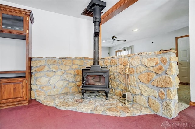 interior details with carpet flooring, ceiling fan, and a wood stove