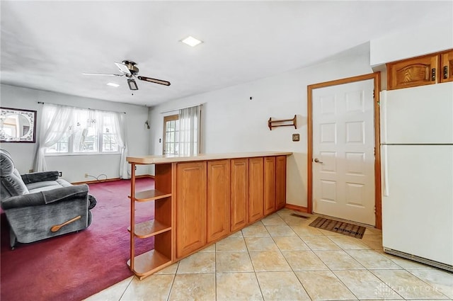 kitchen featuring kitchen peninsula, white refrigerator, light tile patterned flooring, and ceiling fan