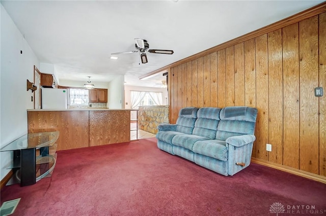 living room with wood walls, ceiling fan, and carpet floors