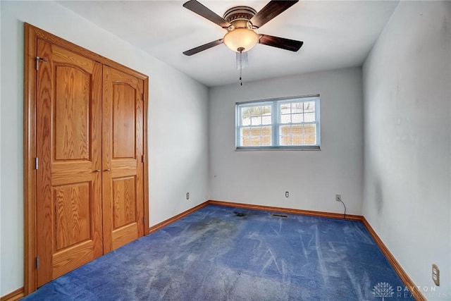 unfurnished bedroom with dark carpet and ceiling fan