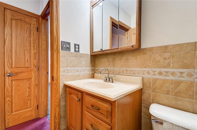 bathroom with toilet, vanity, and tile walls