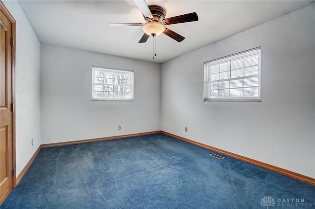 empty room featuring ceiling fan and dark colored carpet