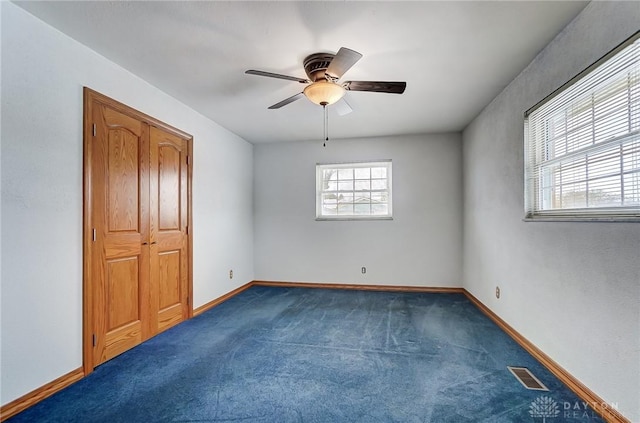 spare room with dark carpet, ceiling fan, and a wealth of natural light